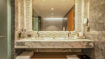 A bathroom with a marble vanity, a large mirror, and a towel rack.