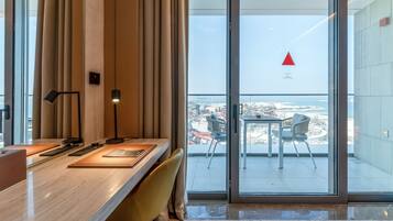 A modern hotel room with a large sliding glass door leading to a balcony with a city view.