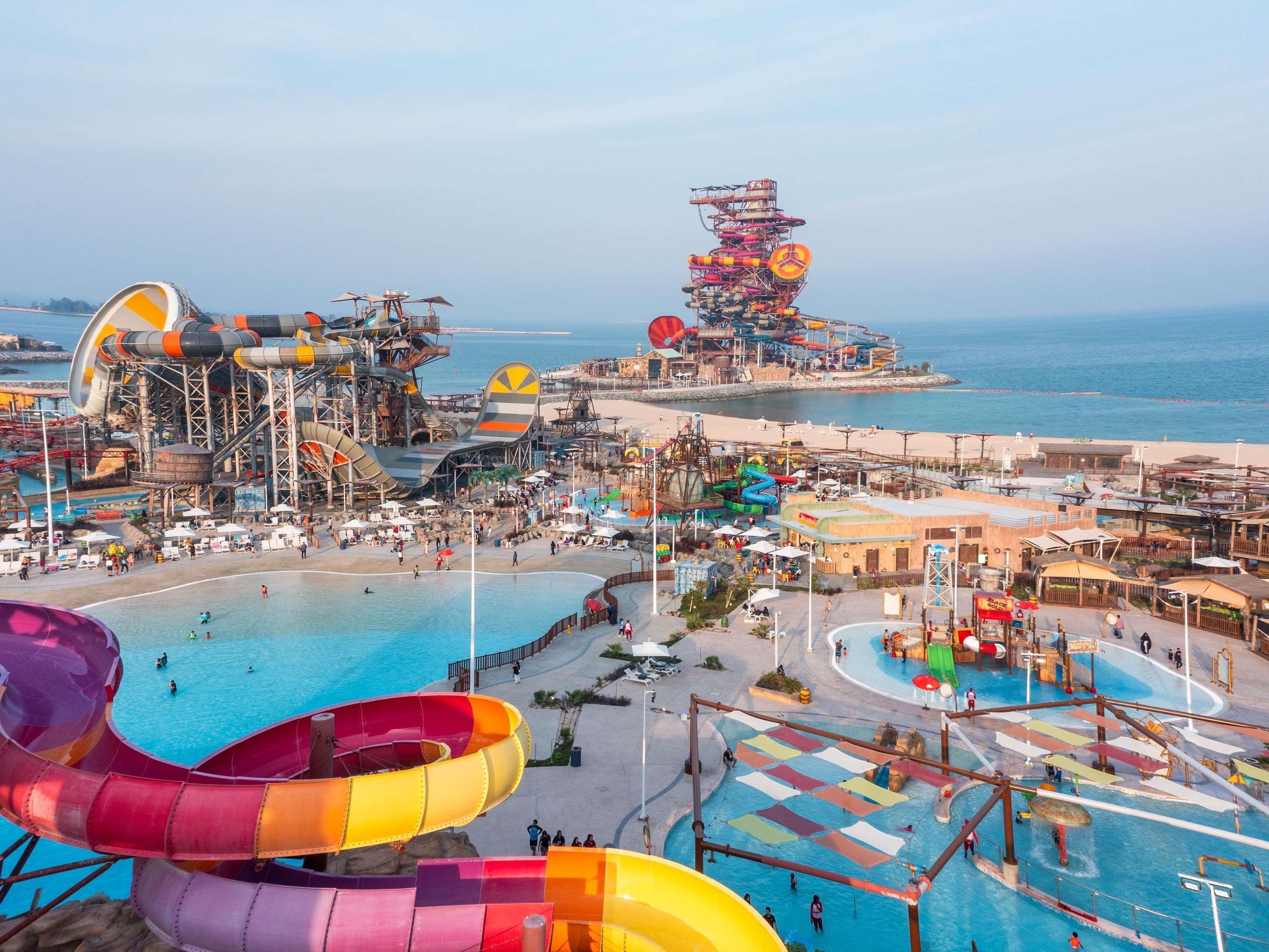 Um parque aquático com vários toboáguas e piscinas, cercado por áreas de praia e vista para o oceano.