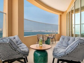 Un balcón con dos sillas, una mesa y vista al mar.