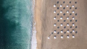 Vista aérea de uma praia com fileiras de guarda-sóis organizados em grade.