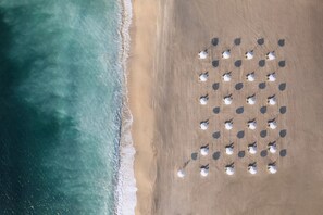 Vista aérea de una playa con hileras de sombrillas dispuestas en forma de cuadrícula.
