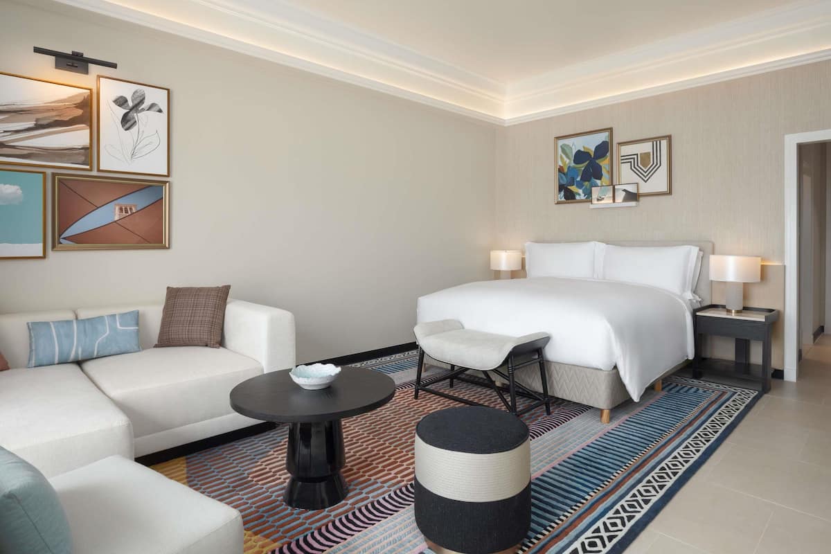 Een hotelkamer met een bed, een slaapbank, een fauteuil, een bijzettafeltje en kunstwerken aan de muur.