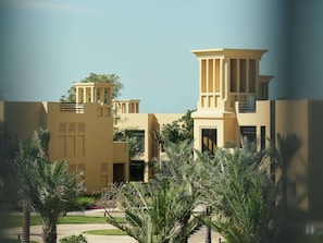 A modern building with a symmetrical facade, large windows, and a central courtyard with palm trees. - Sofitel Ras Al Khaimah Al Hamra Beach Resort (Ras Al Khaimah)
