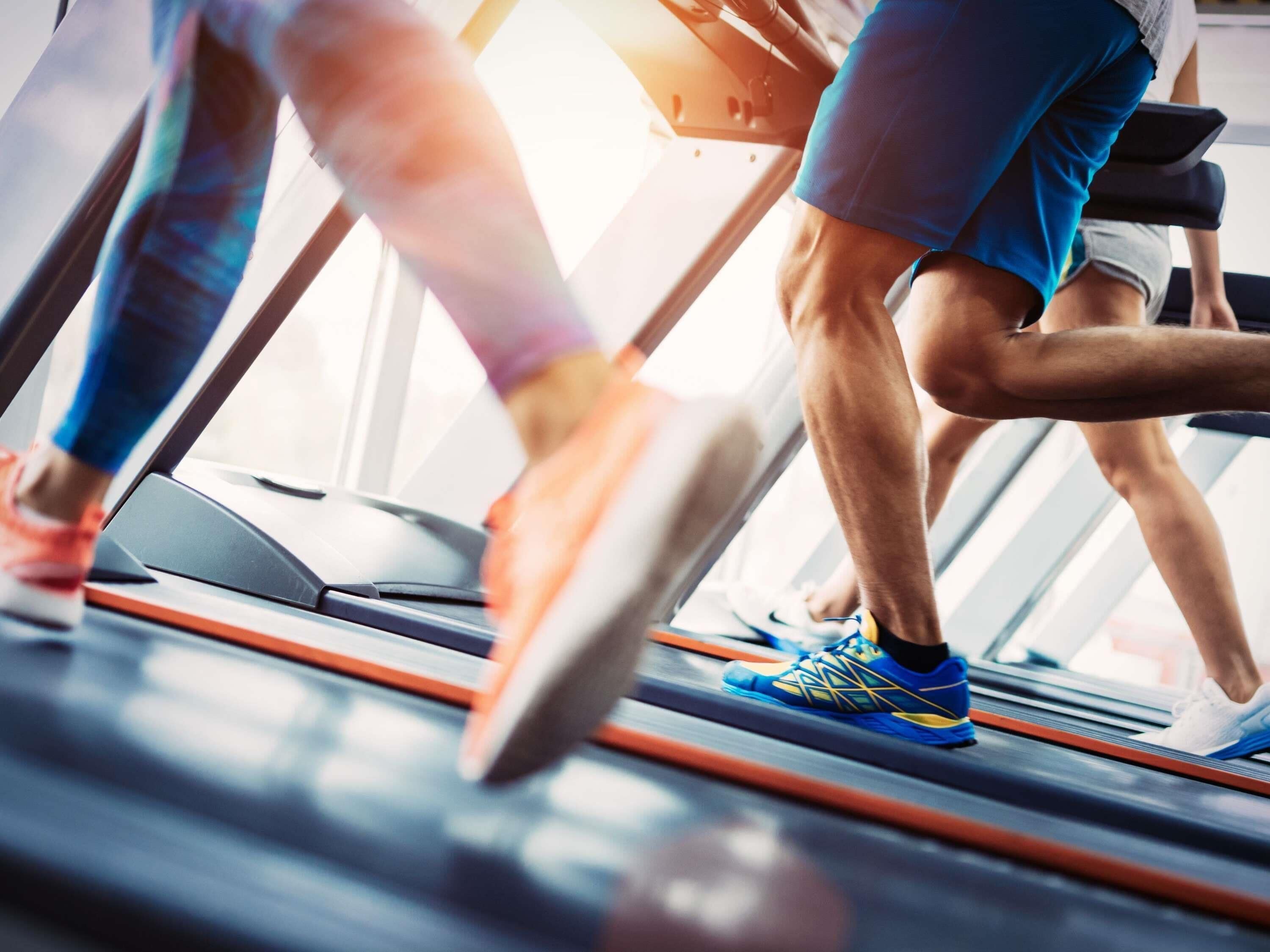 Una persona corriendo en una cinta de correr dentro de un gimnasio.