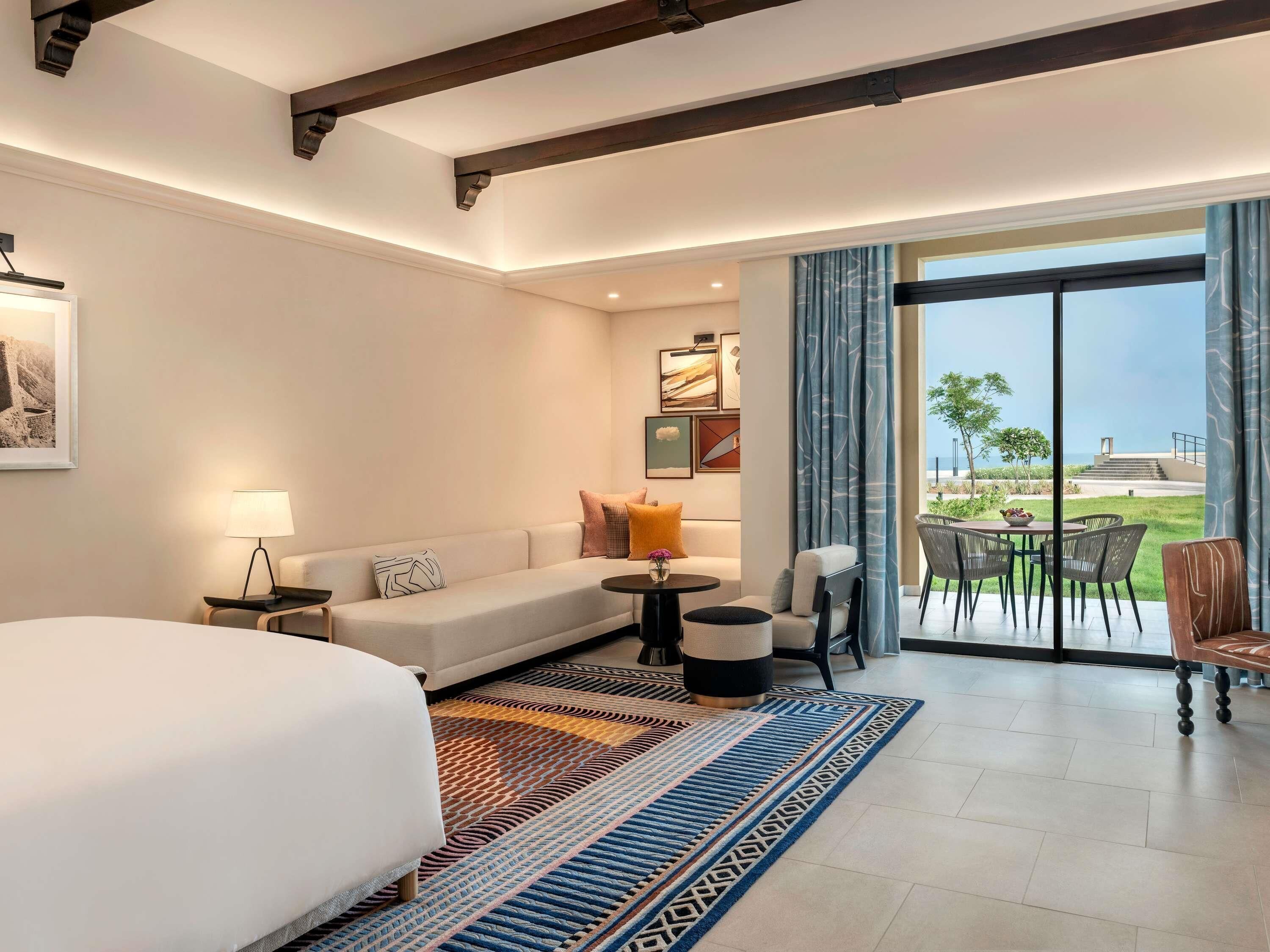 Hotelkamer met een bed, een bank, een kleine tafel, een stoel en een balkon met uitzicht.