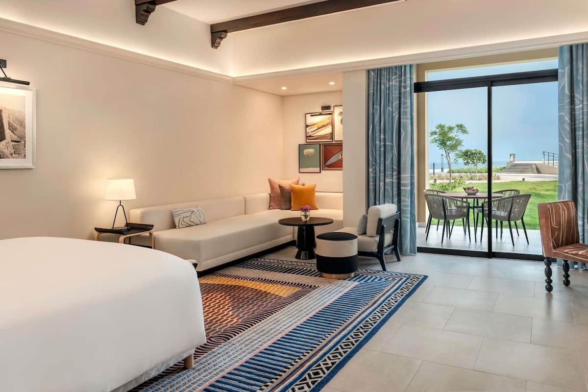 Hotelkamer met een bed, een bank, een kleine tafel, een stoel en een balkon met uitzicht.