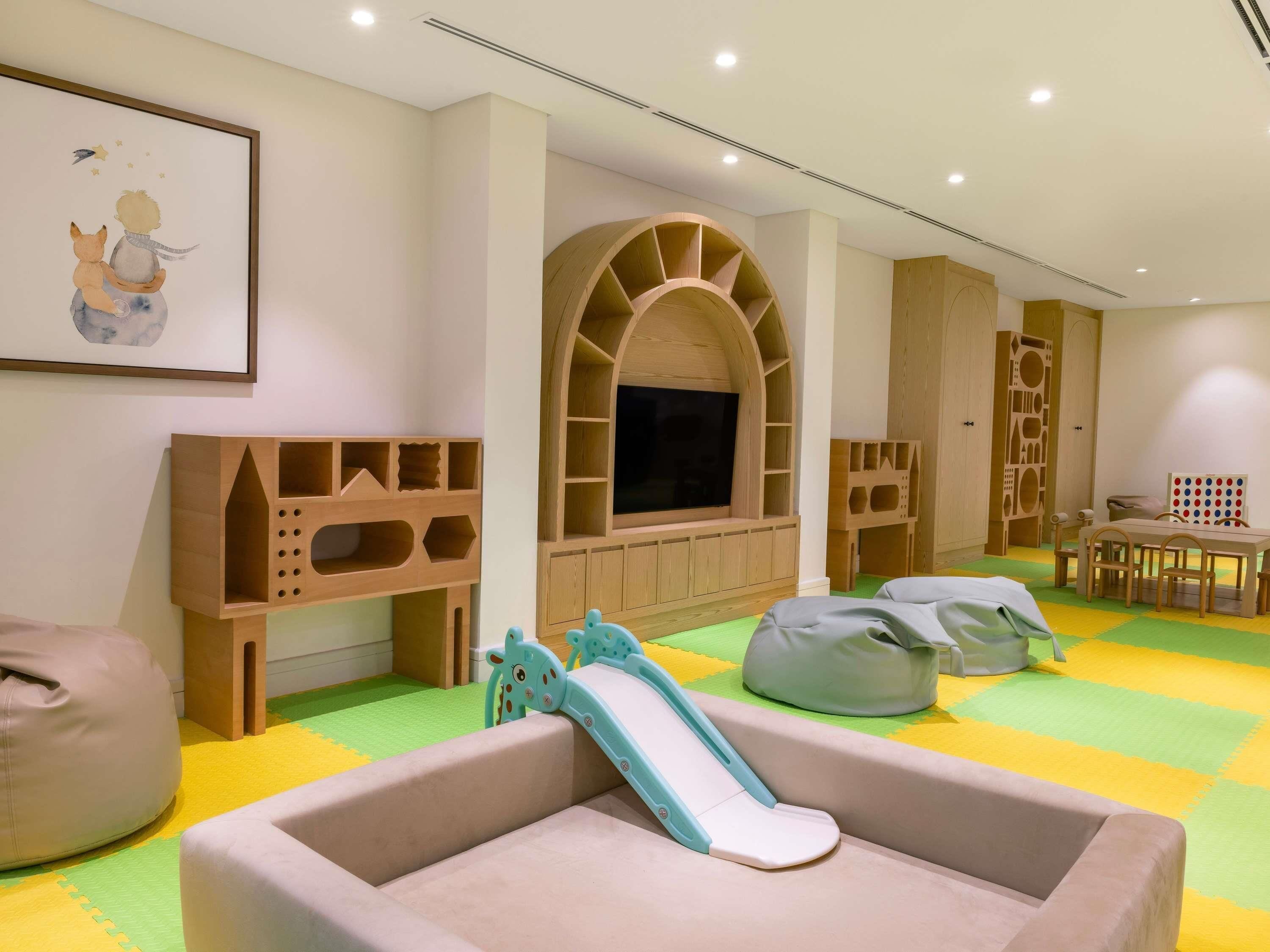 Une salle de jeux pour enfants avec un toboggan, des fauteuils en forme de sac et un téléviseur.
