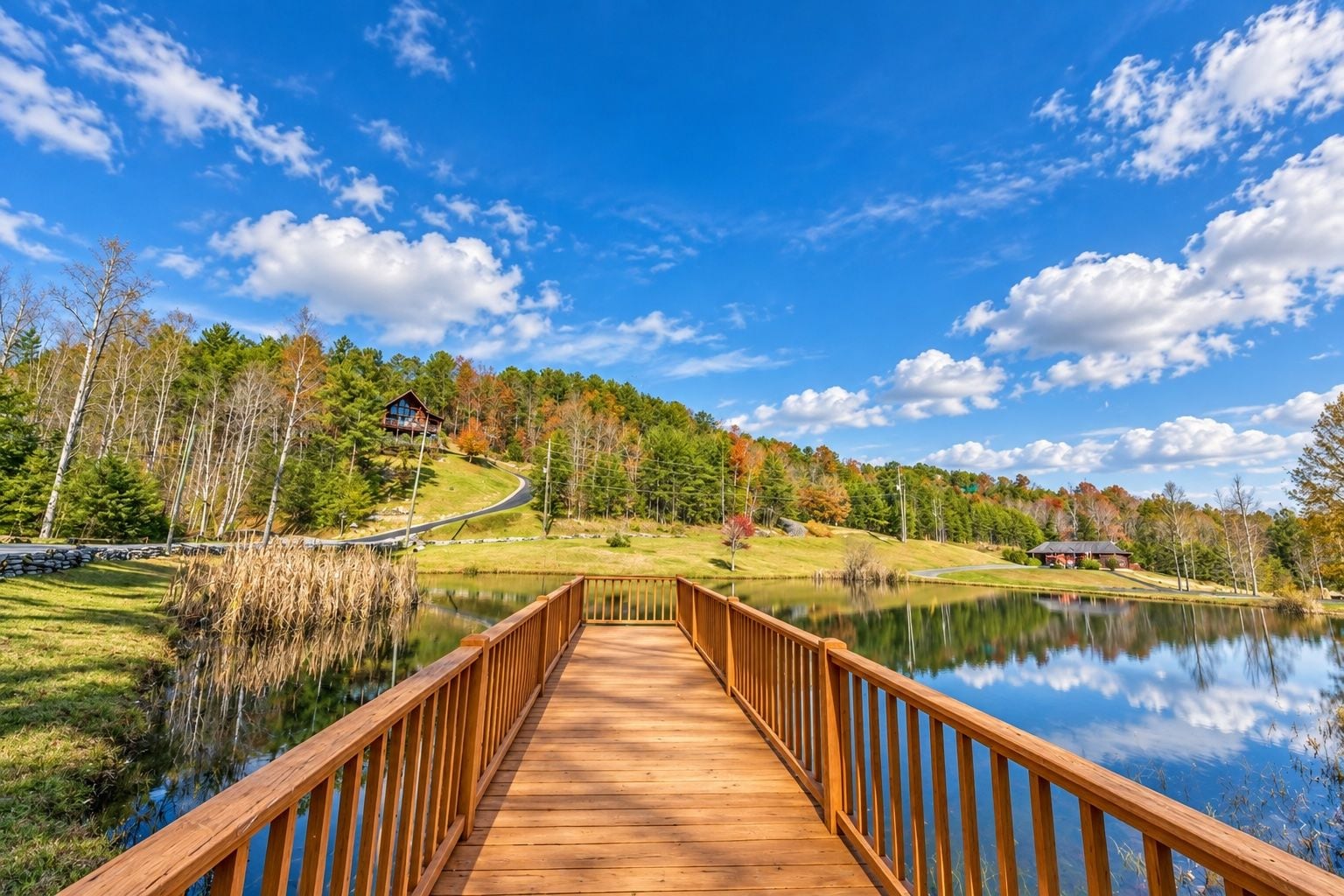 A wooden bridge leading to a house by a lake with a clear sky.