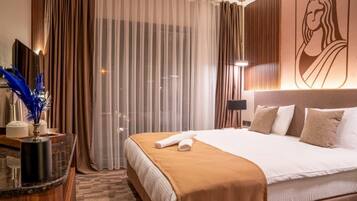 A hotel room with a large bed, a bedside table, a mirror, and a view of the city through the window.