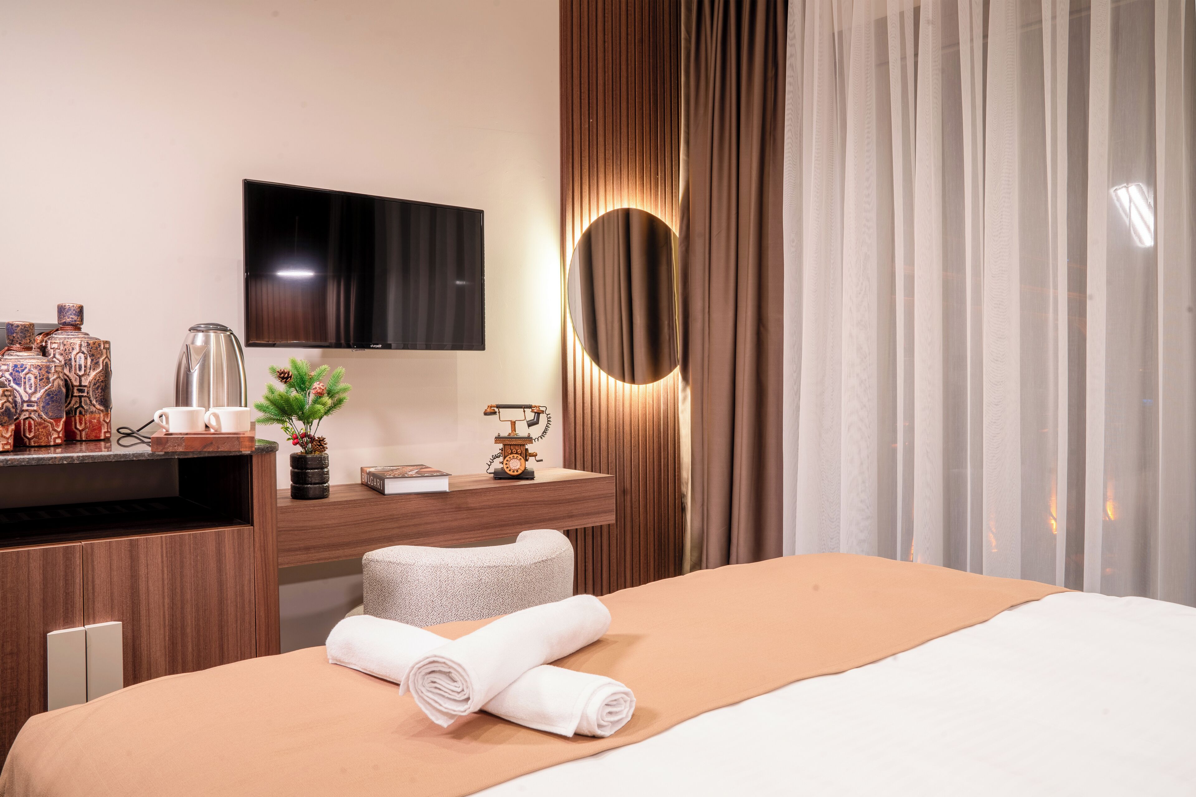 A hotel room with a bed, a desk with a coffee maker, a television, and a mirror.