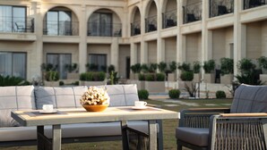 A courtyard with a seating area, a table with a flower arrangement, and a view of a building with arched balconies. - Monalisa Hotels Çanakkale (Çanakkale)