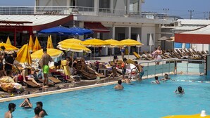 A swimming pool area with multiple sun umbrellas, lounge chairs, and a building with a white roof and large windows. - Monalisa Hotels Çanakkale (Çanakkale)