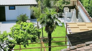 A courtyard with a palm tree, white chairs, and a pergola. - Terrace over VESUVIO/Pompei - Elizabeth's Suite (Terzigno)