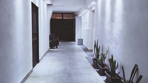 A hallway with white walls, a tiled floor, and potted plants on one side. - Terrace on VESUVIO/Pompei - Mini Suite (Terzigno)