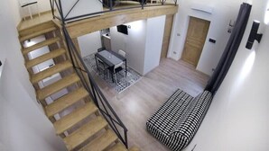 A loft-style room with a wooden staircase, a dining area, and a sofa. - Terrace on VESUVIO/Pompei - Mini Suite (Terzigno)