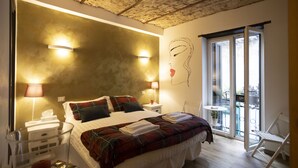 Une chambre à coucher avec un grand lit, deux tables de chevet, une commode, un vase en verre et un balcon avec une chaise.