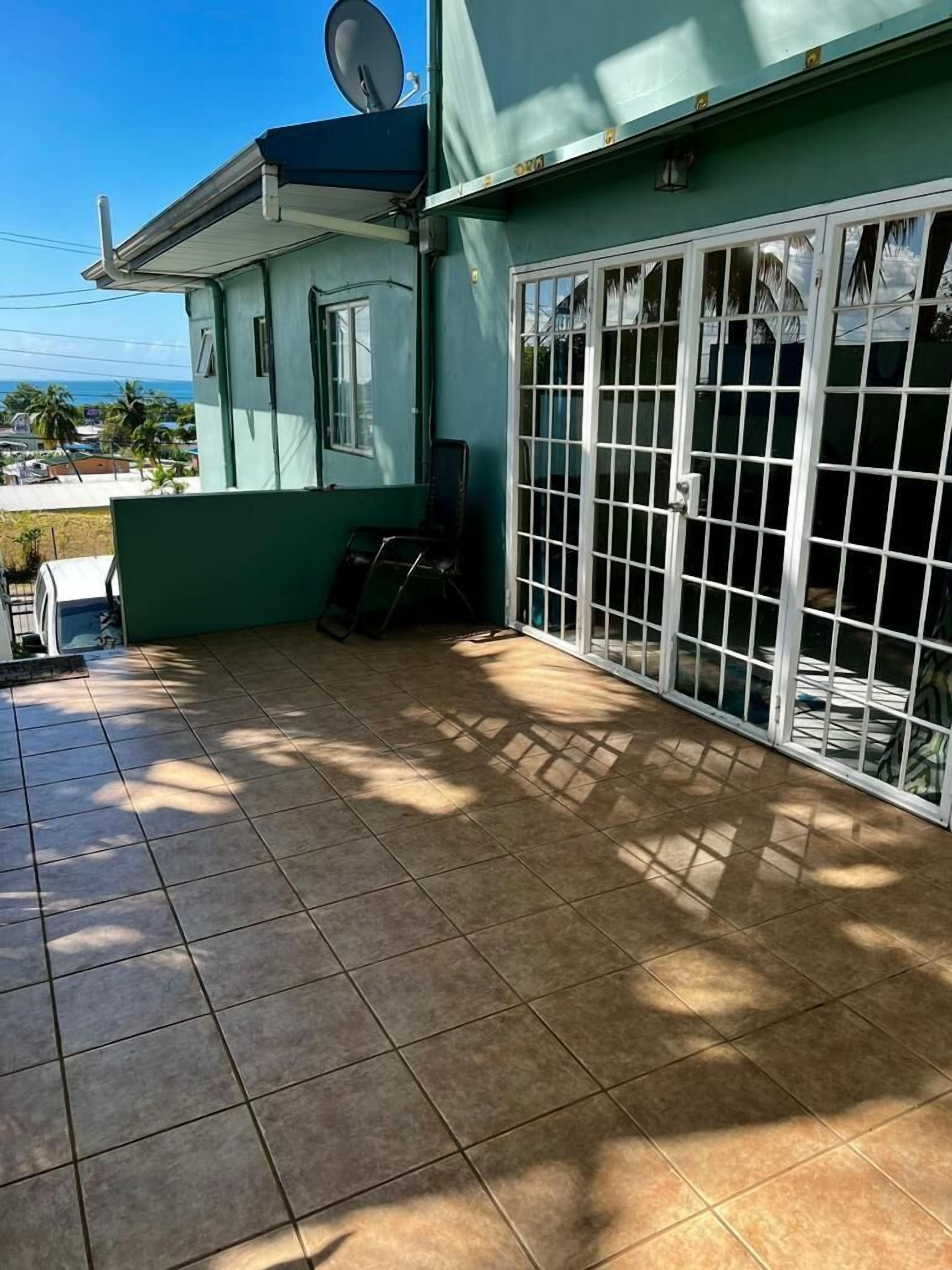 A covered patio area with tiled flooring, a satellite dish, and a sliding glass door with a metal grid.