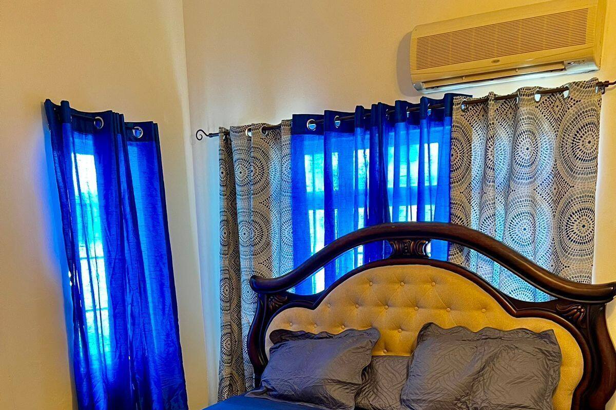 Een bed met een houten frame en een gestapeld hoofdbord, blauw beddengoed en twee kussens.