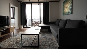 A modern living room with a sofa, a coffee table, and a television. - 9 Palms by Smart City Stays (Cape Town)