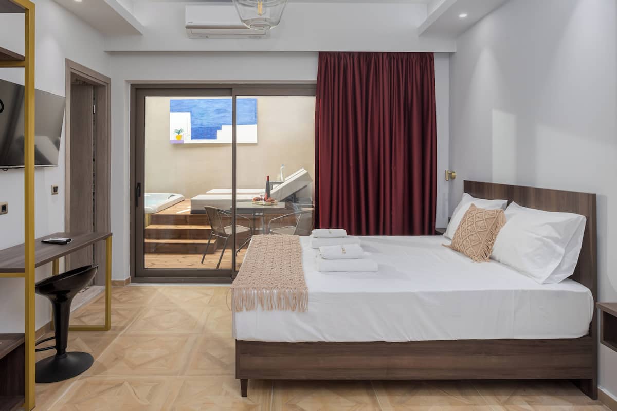 Habitación de hotel moderna con una cama grande, un escritorio y vistas a un balcón.