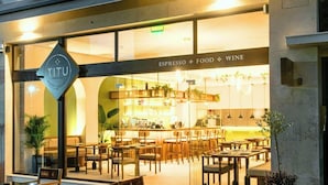 Een restaurant met een bord waarop 'TITU Espresso Food Wine' staat, en een zichtbare bar.