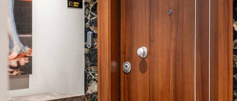 A wooden door with a marble wall and a small sign above it.