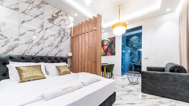 Een moderne hotelkamer met een groot bed, een houten scheidingswand, een zithoek en uitzicht op de stad.
