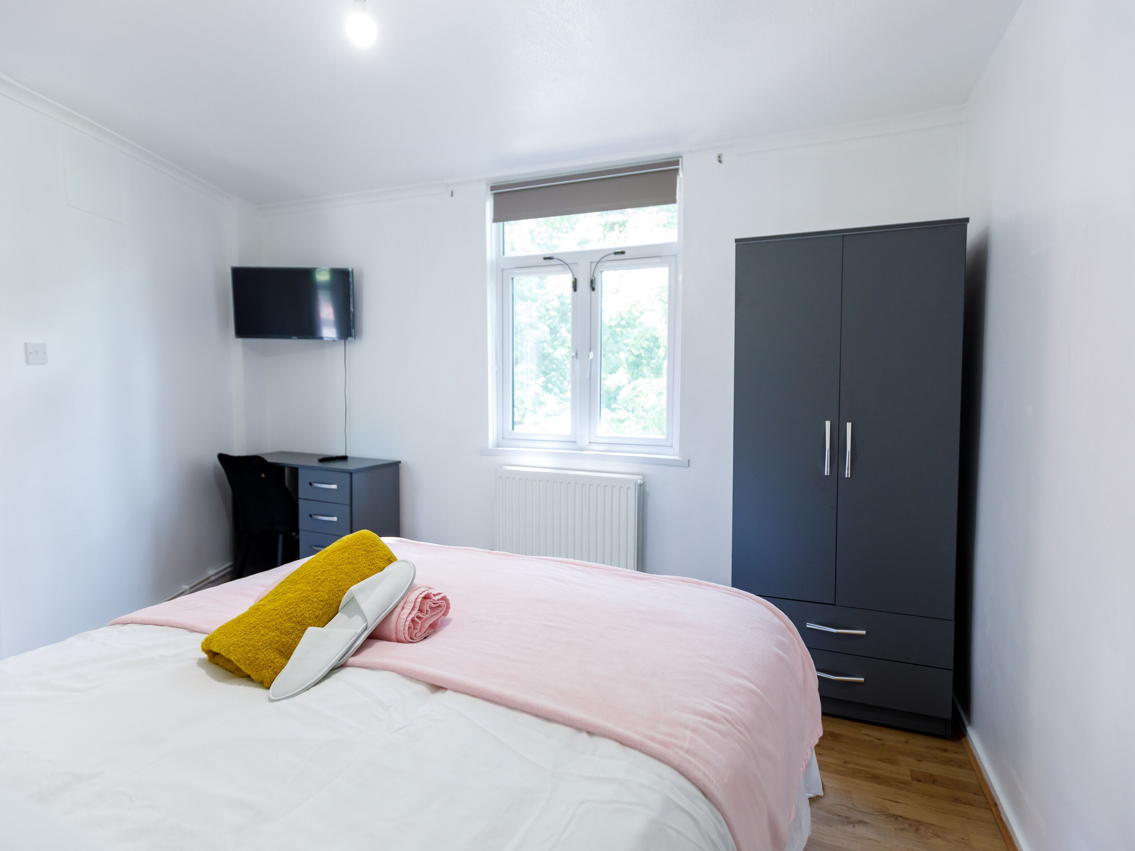 Un dormitorio con cama, armario, escritorio y televisor.