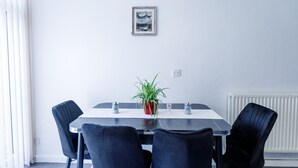 A dining area with a rectangular table, four black chairs, a potted plant, and a framed picture on the wall. - Inviting 3-bed House in London, Stay up to 6 (London)