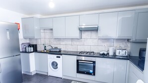 A modern kitchen with stainless steel appliances, a built-in oven, and a washing machine. - Inviting 3-bed House in London, Stay up to 6 (London)
