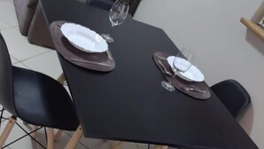 A dining table with four chairs, two wine glasses, and plates set for two.