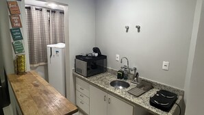 A compact kitchen with a microwave, coffee maker, and sink.