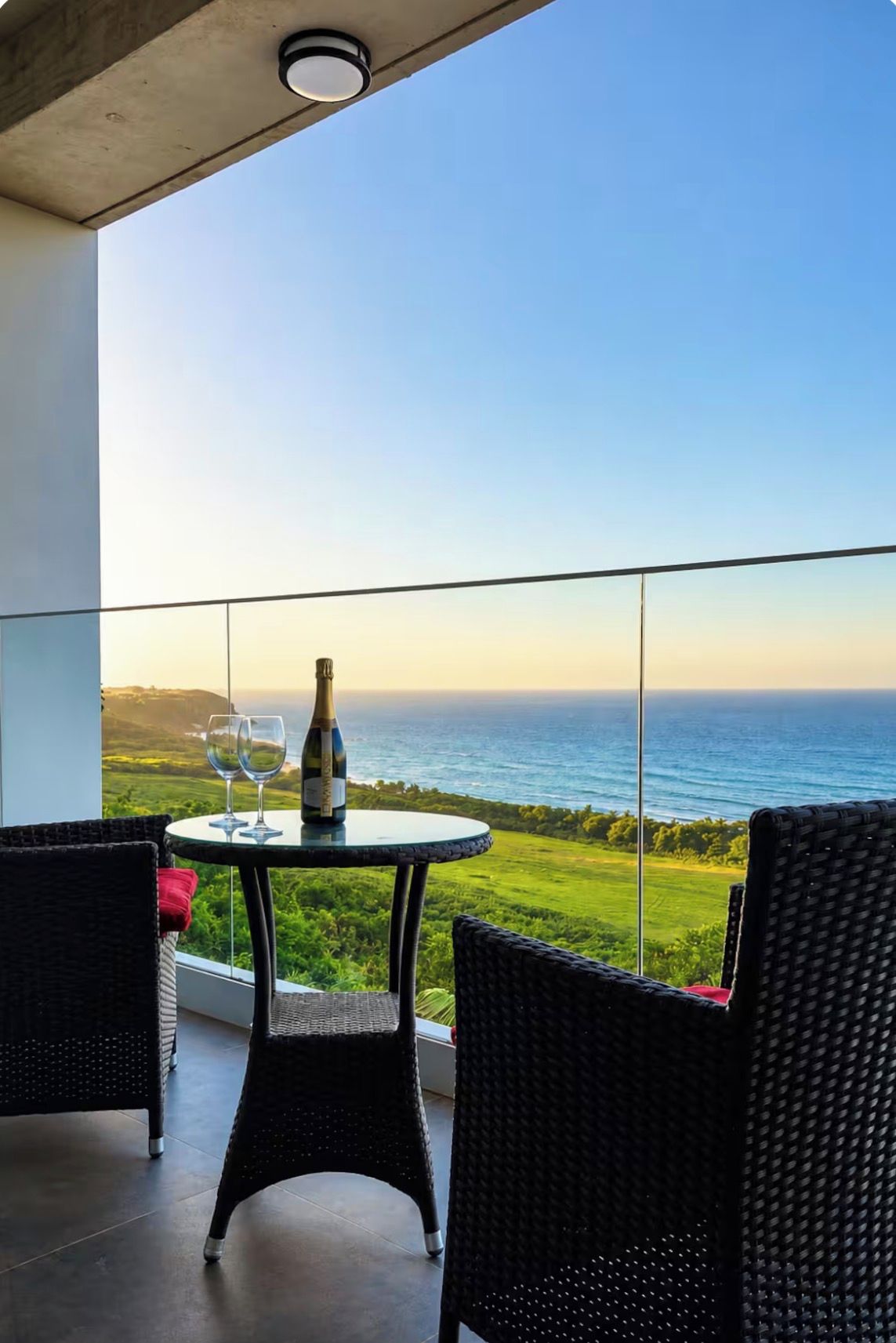 A balcony with a table, two chairs, and a bottle of champagne.