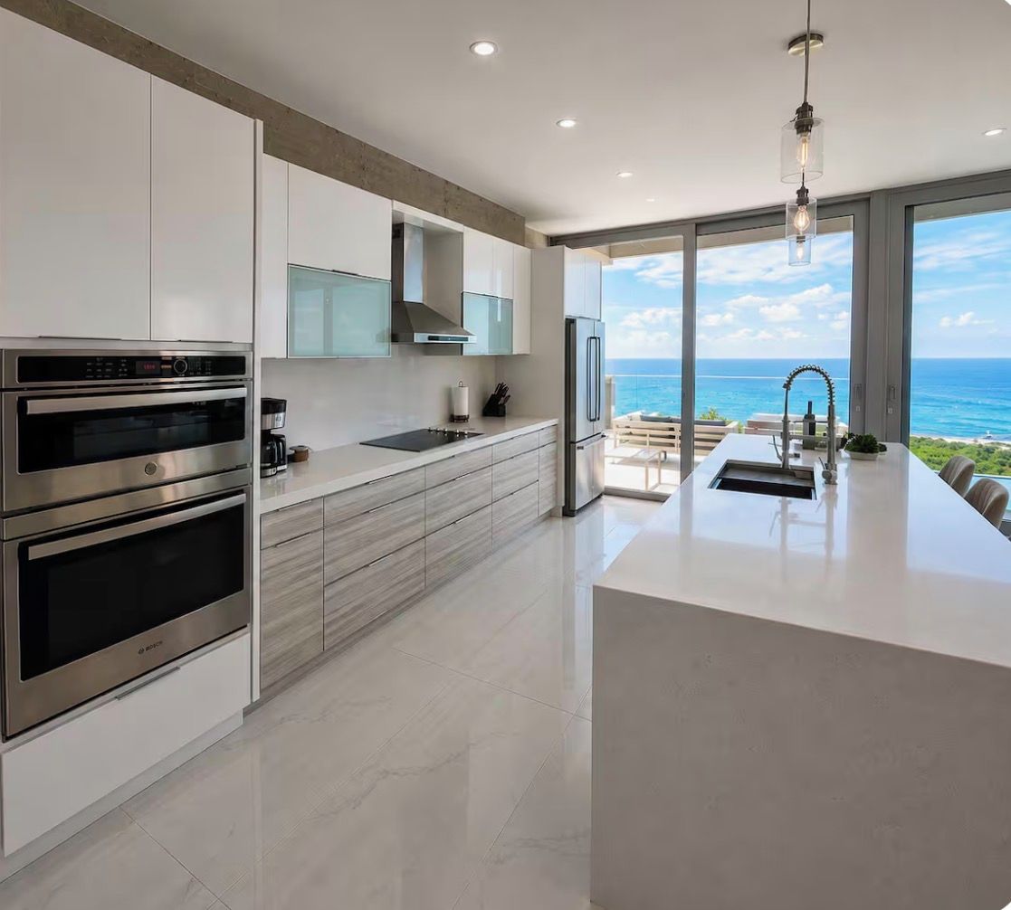 A modern kitchen with built-in appliances, a large island, and a view of the ocean.