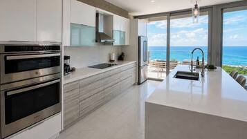 A modern kitchen with built-in appliances, a large island, and a view of the ocean.