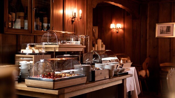 A buffet setup with glass-covered food displays, wooden tables, and wall-mounted lighting.