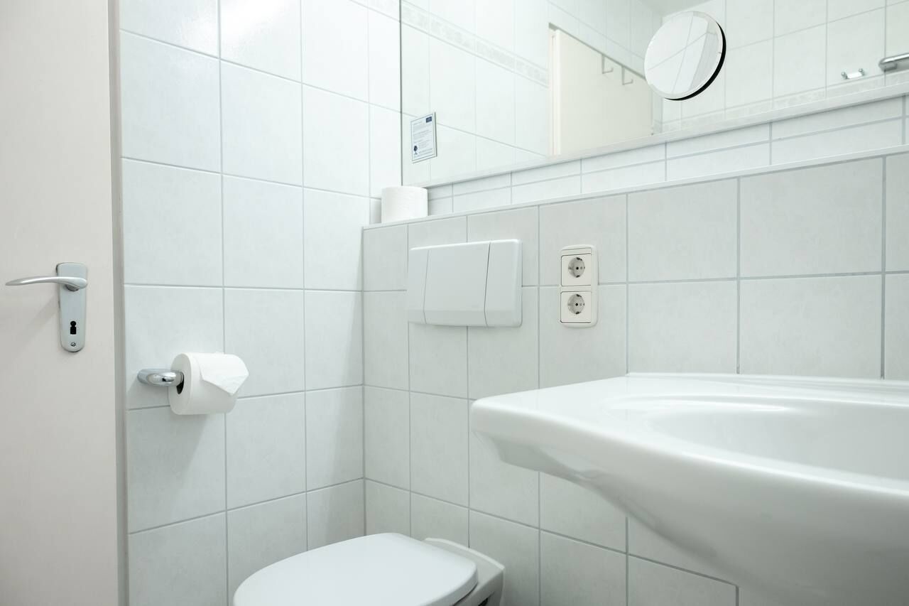 A modern bathroom with a toilet, sink, and mirror.