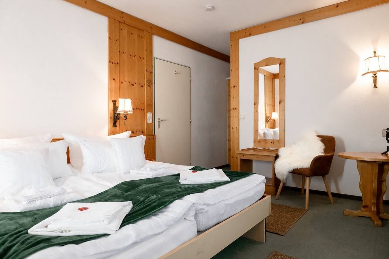 Une chambre d’hôtel avec un lit, un bureau, une chaise et un miroir.