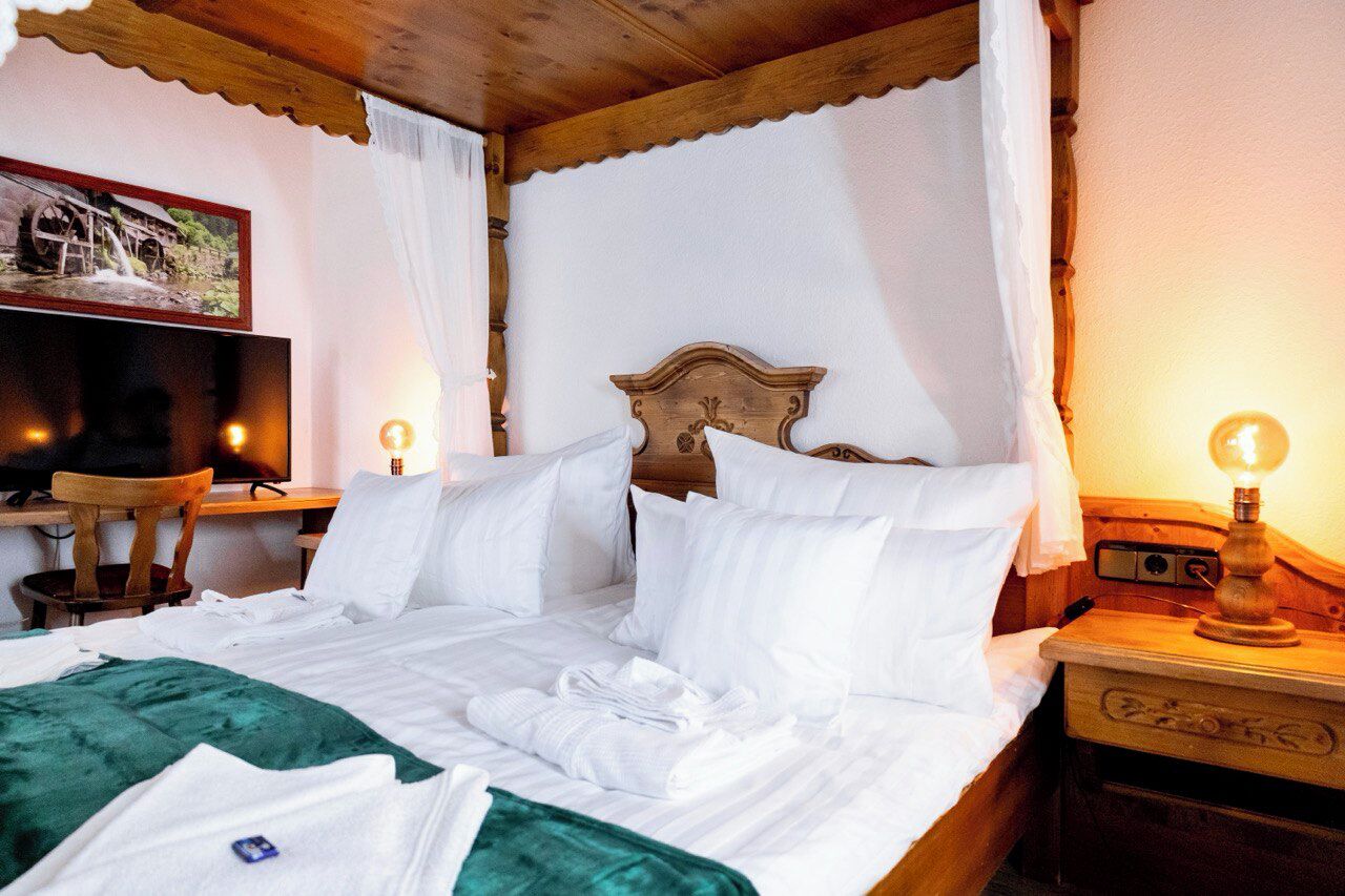 A neatly made bed with white linens, a wooden headboard, and a bedside table with a lamp.