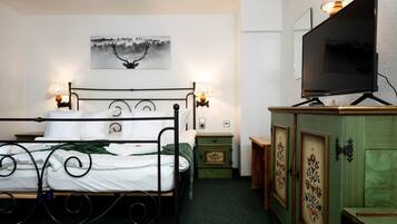 A bedroom with a bed, bedside lamps, a television, a cabinet, and a painting on the wall.