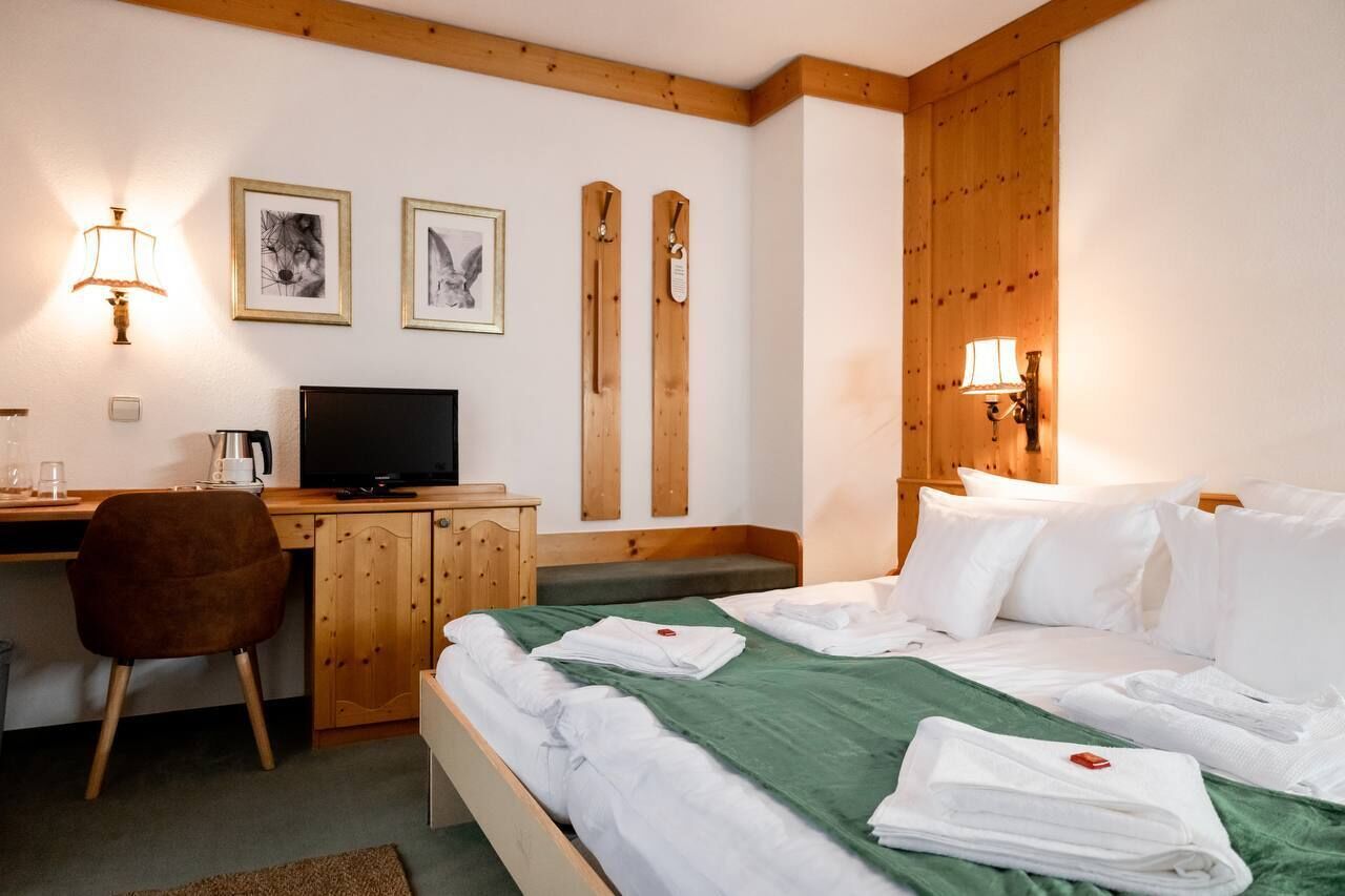 Una habitación de hotel con cama, escritorio, silla y dos lámparas de pared.