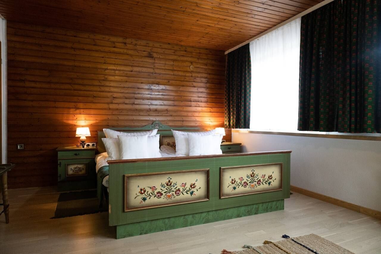 A wooden-paneled bedroom with a bed, nightstands, and a window with curtains.