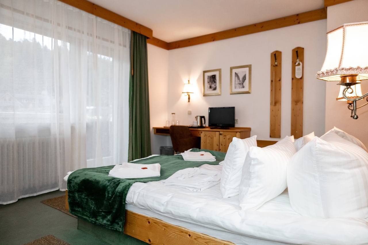 A hotel room with a bed, a desk, a lamp, and a television.
