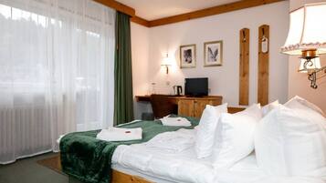 A hotel room with a bed, a desk, a lamp, and a television.