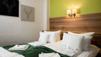 Ein Hotelzimmer mit einem Holzkopfteil, zwei Wandlampen, einer grünen Akzentwand und Bildern von Hirschköpfen.