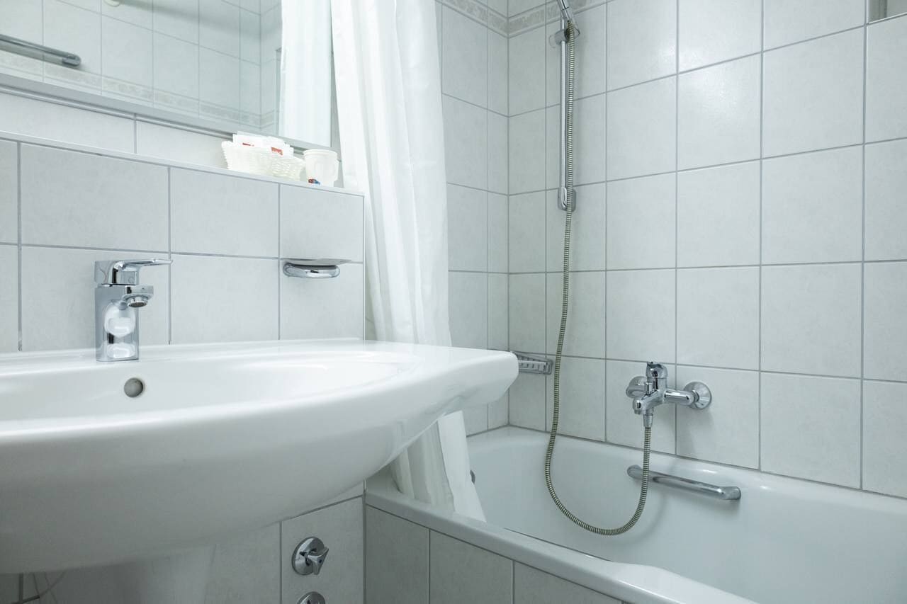 A bathroom with a white sink, a mirror, a shower, and a bathtub.