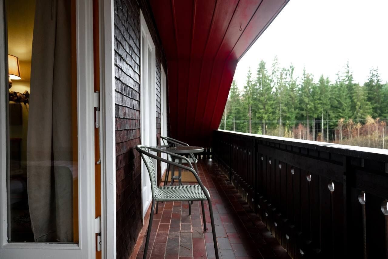 A balcony with a red roof, a brick floor, and a metal railing.