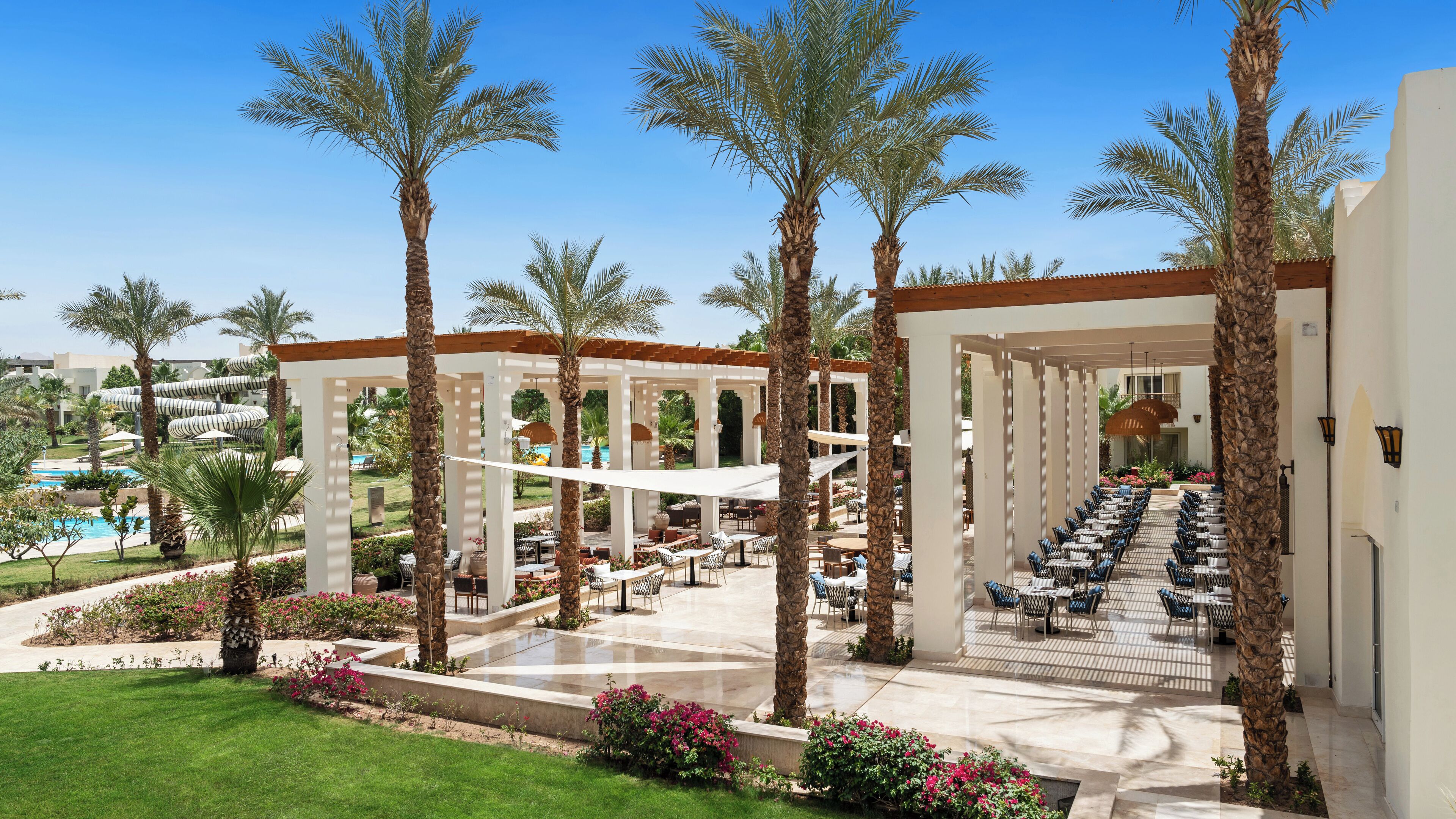 Een resort met buitenzitgedeeltes, palmbomen en een zwembad.