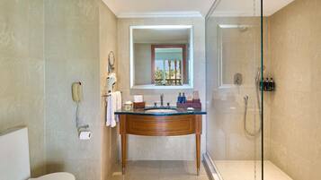 Une salle de bain comprenant des toilettes, un lavabo avec un miroir, une douche et un espace de douche délimité par des parois en verre.